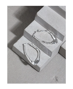 Close-up of S925 sterling silver earrings with irregular organic design on stone surface