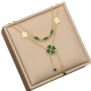 Double-layered gold necklace with emerald heart, clover charms and long tassels in a box