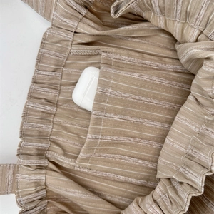 Detail view of the interior pocket in a striped canvas tote bag holding wireless earbuds