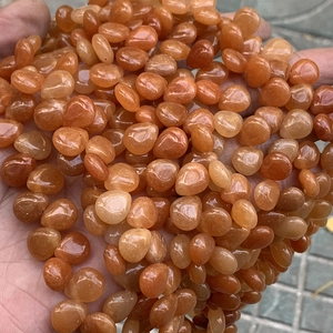 Macro detail of natural orange agate teardrop beads held in hand for DIY jewelry making