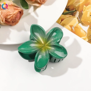 Detailed close-up of a dark green floral hair claw with glitter accents on white surface