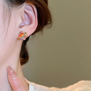 Macro shot of colorful floral crystal earrings with vibrant rhinestones on the ear