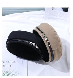 Close-up of retro beret featuring metallic star chain and leather trim details