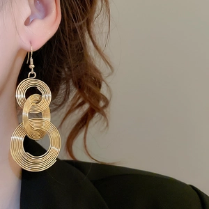 Detail of gold hollow triple hoop earrings with intricate metal wire wrapping texture