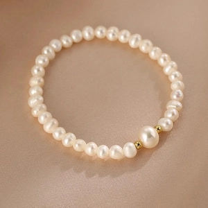 Detailed view of elegant freshwater pearl bracelet on champagne silk fabric background