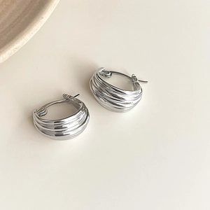Macro detail of silver hoops featuring a multi-layered wavy texture and metallic finish