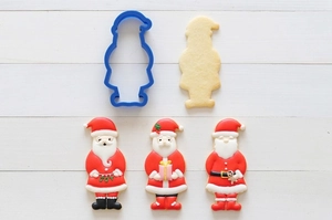 Detail of blue plastic Santa Claus cookie cutter and decorated biscuits with JOY lettering
