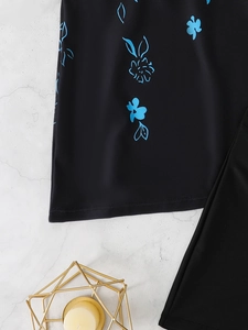 Detailed flat lay of black tankini featuring elegant blue floral prints on marble surface