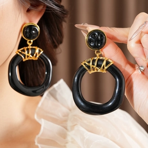 Détail de boucles d'oreilles créoles vintage en résine noire avec attaches dorées