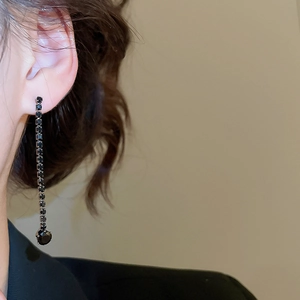 Close-up of elegant long black faceted gemstone earrings worn on a model's ear