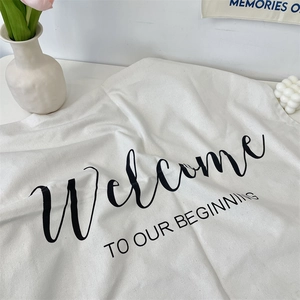 Minimalist white canvas decor mat with black Welcome TO OUR BEGINNING artistic typography