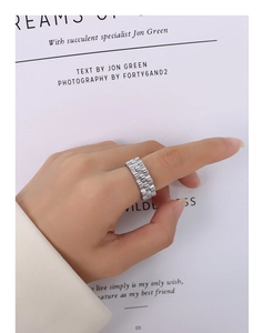 Macro detail of silver watch strap style ring with polished links on a finger