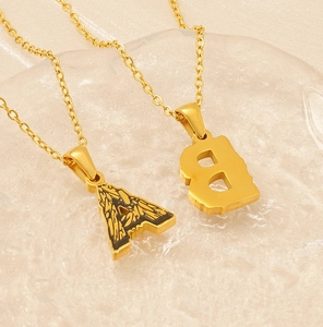 Macro detail of 18k gold plated letter A and B pendants on a textured display base