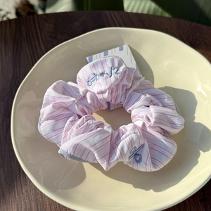 Detail of pink striped scrunchie with blue mathematical embroidery in a ceramic plate