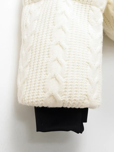Detail of cable knit white sweater sleeve with black windproof ribbed inner cuff
