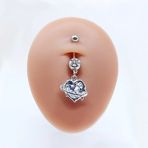 Close-up of heart-shaped silver belly button ring with clear cubic zirconia on skin