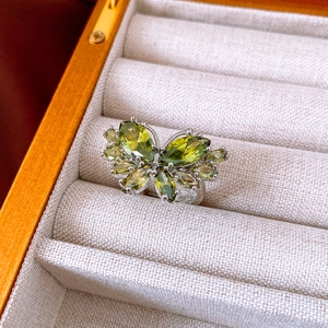 Detailed close-up of butterfly ring with green stones in a wooden jewelry box