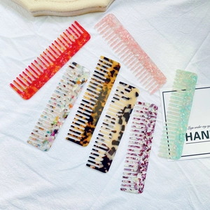 Flat lay of colorful marble pattern acetate combs on elegant white fabric background
