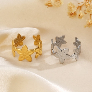 Anelli a fiore in oro 18K e argento su raso beige con accenti floreali
