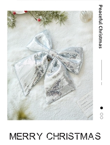 Close-up of sparkling silver sequin Christmas bow with pine needles and festive berries