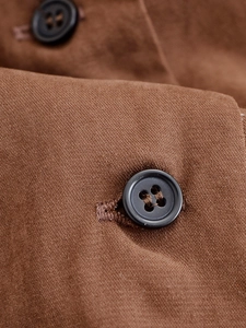 Macro shot of dark brown woven fabric texture and black four-hole resin button details