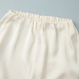 Close-up of elastic waistband on ivory satin straight leg trousers with silk texture