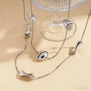 Minimalist silver irregular geometric necklace with liquid metal pendants on a glass tray