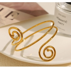Detail of a golden spiral open cuff bracelet with polished finish and stylish design