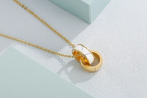 Close-up of interlocking gold rings necklace with elegant white marble texture inlay