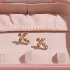 Elegant gold vintage cross earrings with clear crystals on a pink velvet jewelry box display
