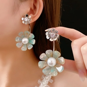 Close-up of elegant flower earrings featuring crystals, pearl centers, and acrylic petals