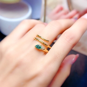 Detail of golden snake ring featuring pear-cut green gemstone and intricate scale texture