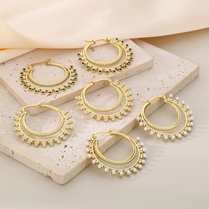 Detail of vintage double-layer gold earrings with pearls and black beads on stone