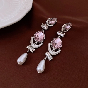 Detail of silver drop earrings featuring pink crystals and white pearls on silk