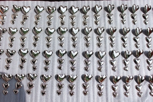 Vue détaillée de boucles d'oreilles triple cœur en argent disposées en étalage de gros