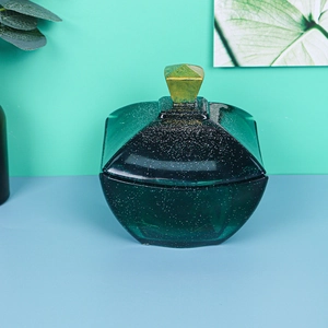 Frasco de vidrio verde oscuro con purpurina dorada y asa de metal geométrica