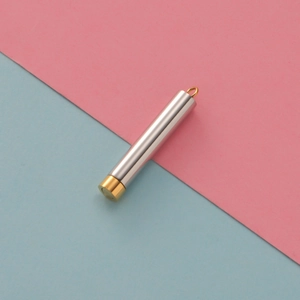 Polished stainless steel cylindrical pendant with a gold cap and ring detail on top