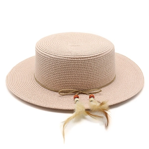 Detail of a straw hat featuring a string band with decorative beads and soft feathers