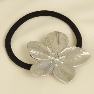 Macro detail of silver stainless steel 5-petal flower ornament on black elastic hair tie