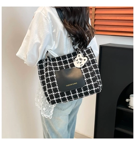 Detail of checkered tote bag featuring a leather pocket and cute tiger pendant charm
