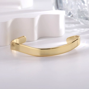 Irregular gold-plated brass bangle with minimalist sleek polished streamlined design