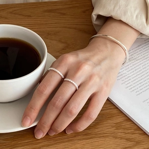 Close-up of a minimalist silver bangle and two sparkling diamond rings on a hand