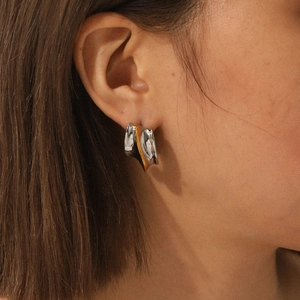 Modern two-tone gold and silver stainless steel earrings worn by a model for a stylish look