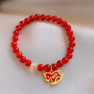 Detail of red beaded bracelet with golden horse charm and success engraving