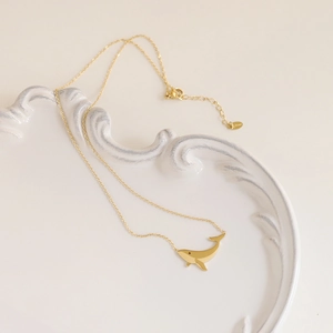 Bohemian whale pendant necklace in 18K gold plated stainless steel on a white tray