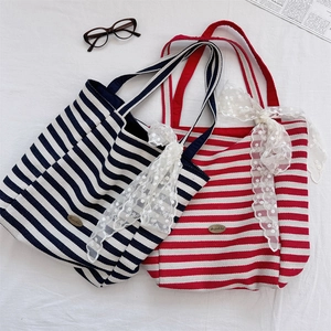 Close-up of double-sided striped canvas tote bag with decorative lace bow and brand logo