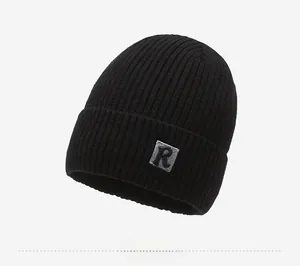 Close-up of black ribbed knit beanie with R-letter square patch detail for winter