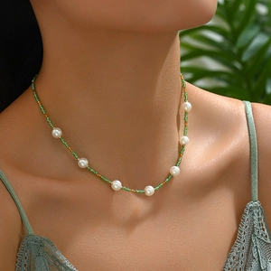 Bohemian woven beaded necklace with white pearls and green seed beads on a female model