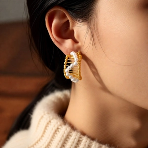 Detailed view of 18k gold plated pearl C-shape wrap earrings on model with knit sweater