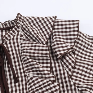 Detail view of the V-neck ruffle layers and brown plaid pattern on a women's blouse